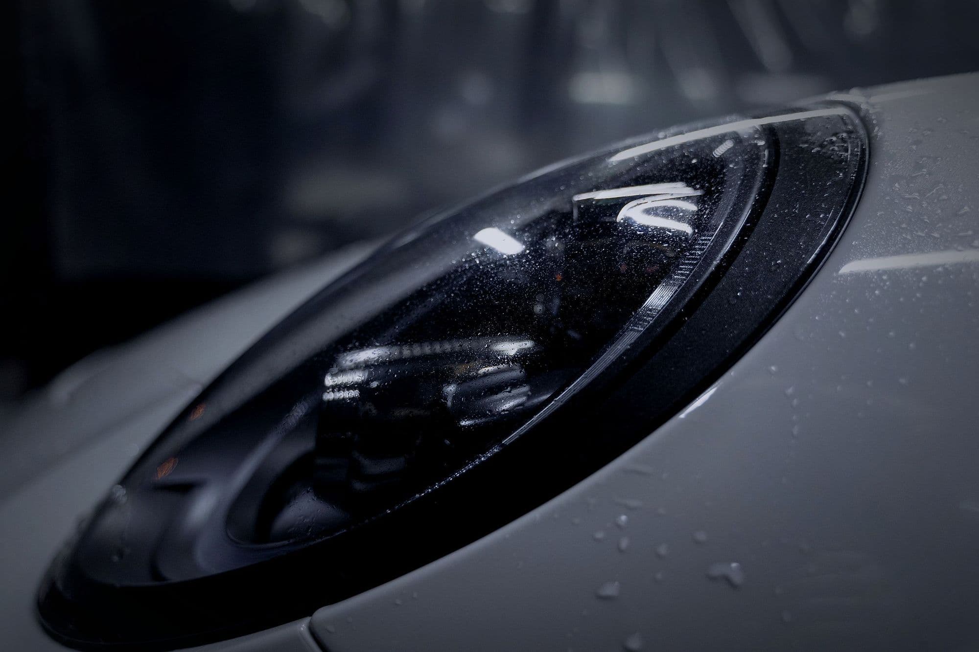 The 911's headlamp, with water beading on the paint.