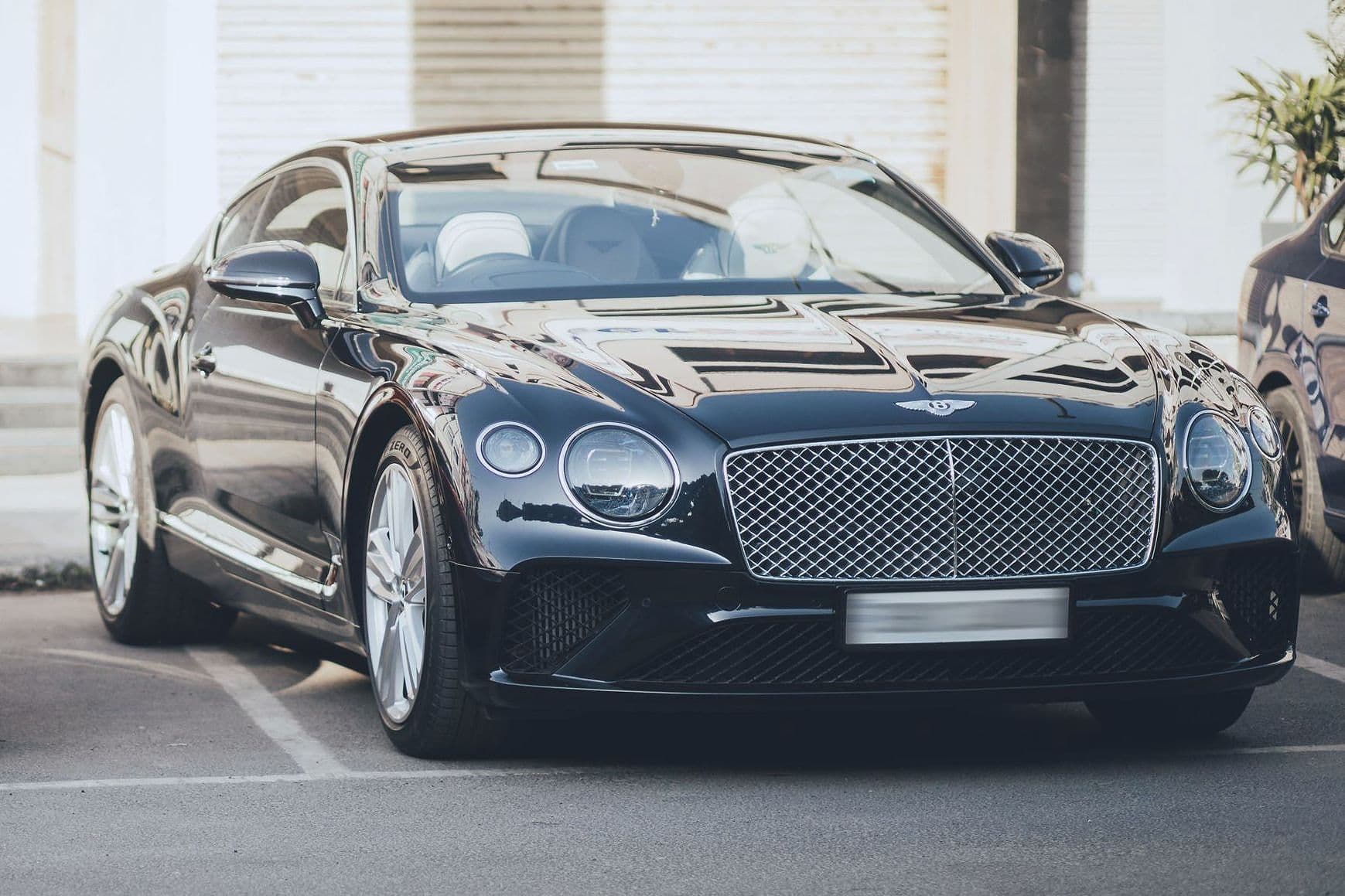 A dark blue Bentley Continental GT parked in front of closed shutters.