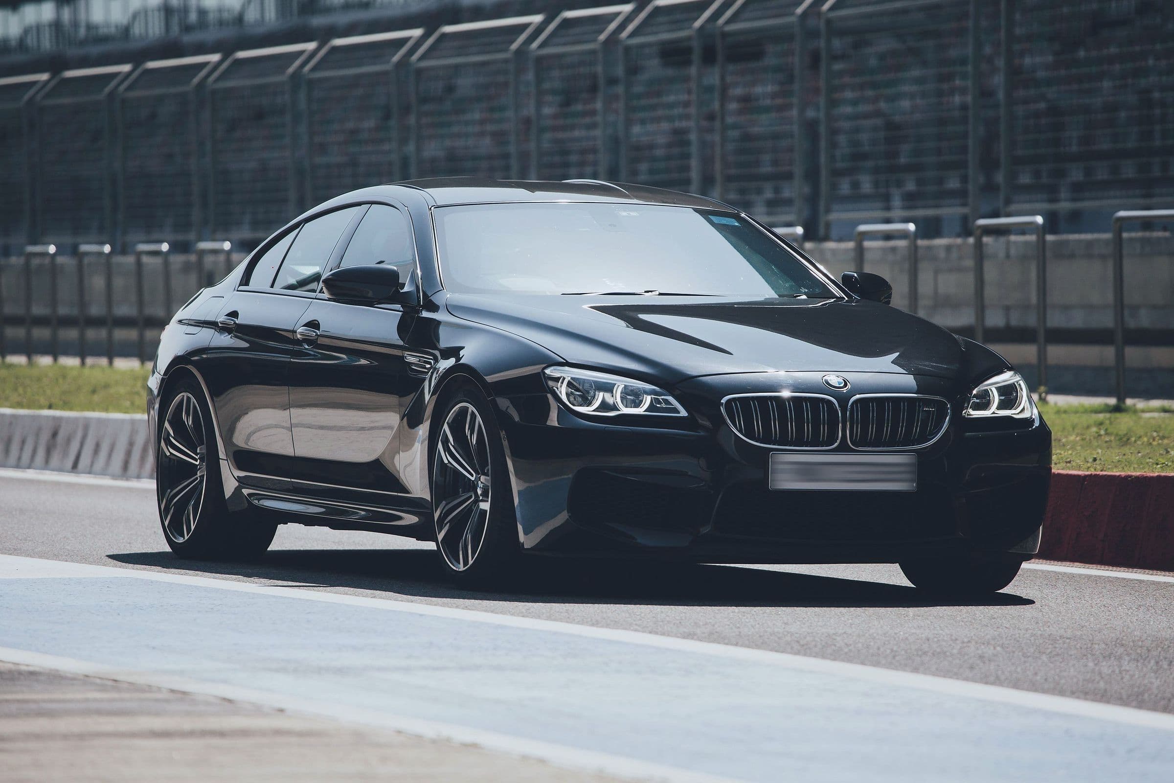A black BMW M6 Gran Coupé in bright sun, front three-quarter.