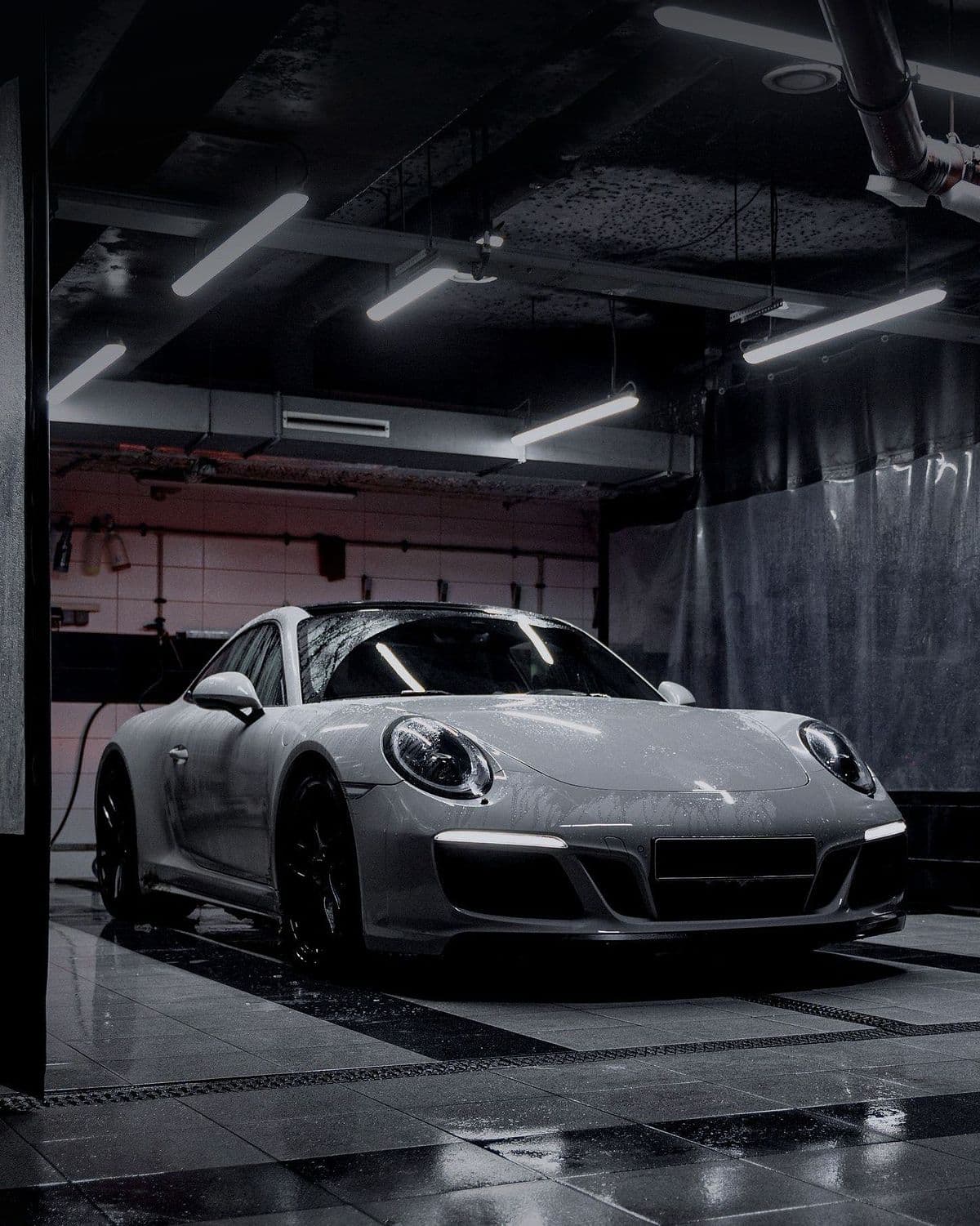 The silver-grey 911 in the preparation bay, front three-quarter.