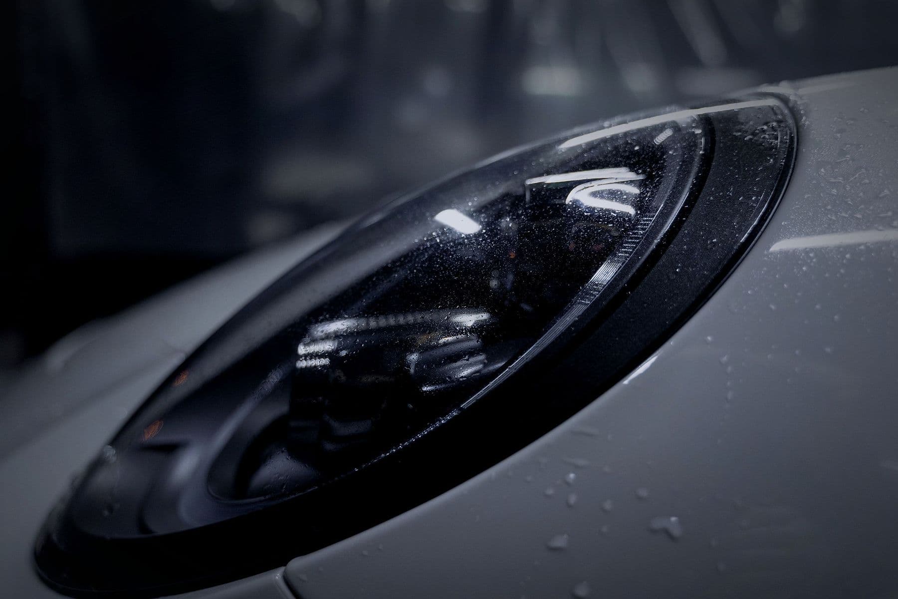 The 911's headlamp, with water beading on the paint.