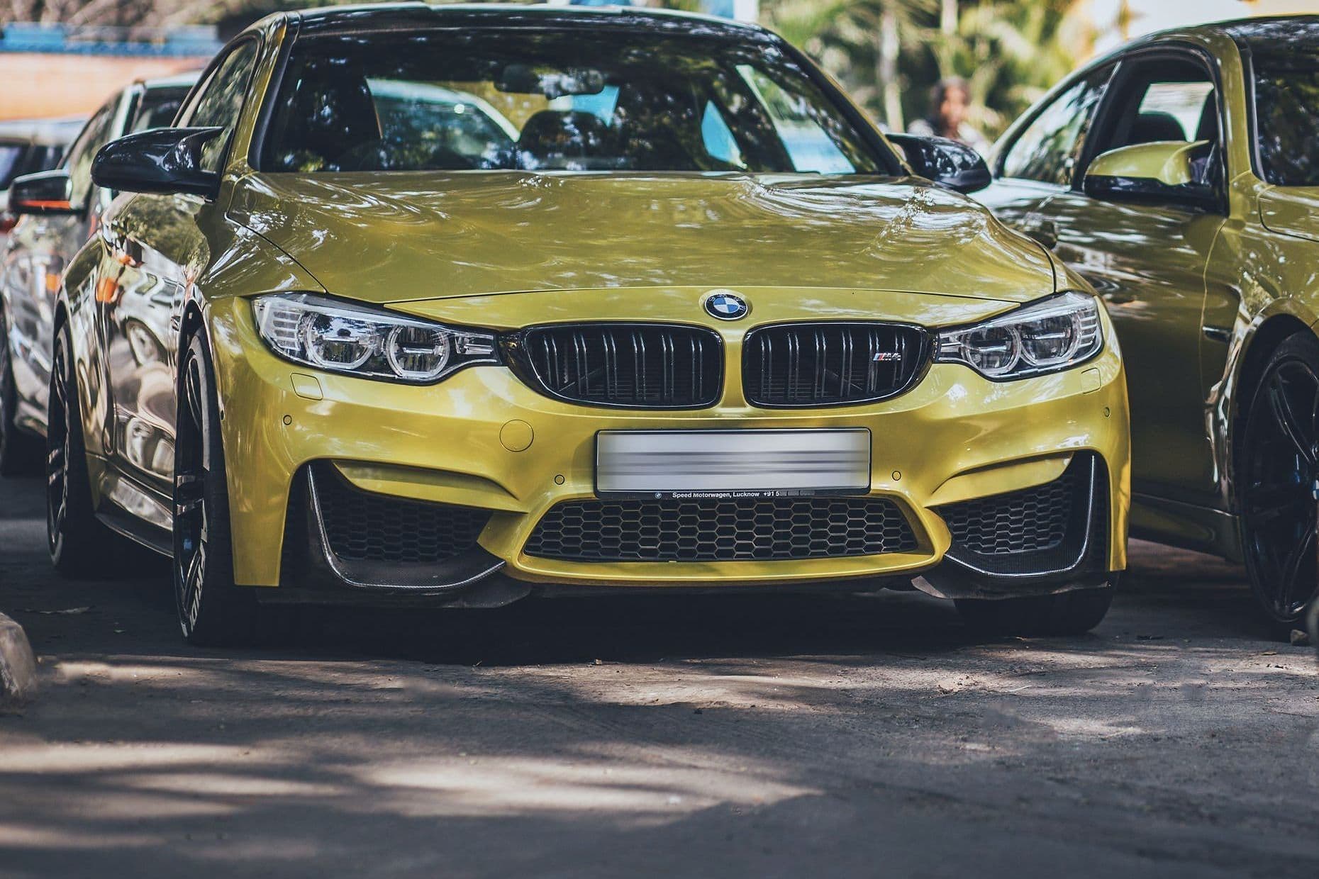 A yellow BMW M4 head-on, a second yellow M4 parked behind it.