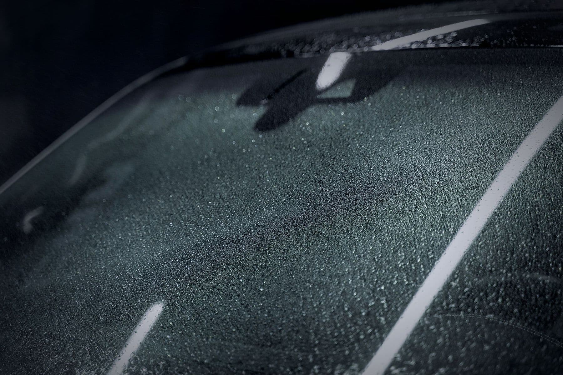 Water beading on a windscreen under the strip lights.